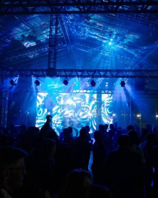 Estrutura de palco com iluminação azul e público em evento produzido pela Light